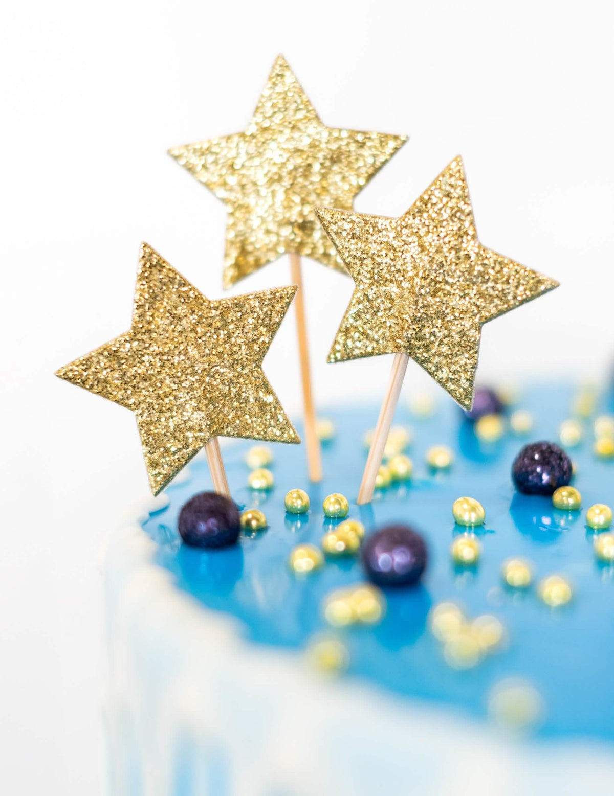 Prim-plan pe sclipiciul auriu al cake topper-ului pe pic stea pentru aniversare