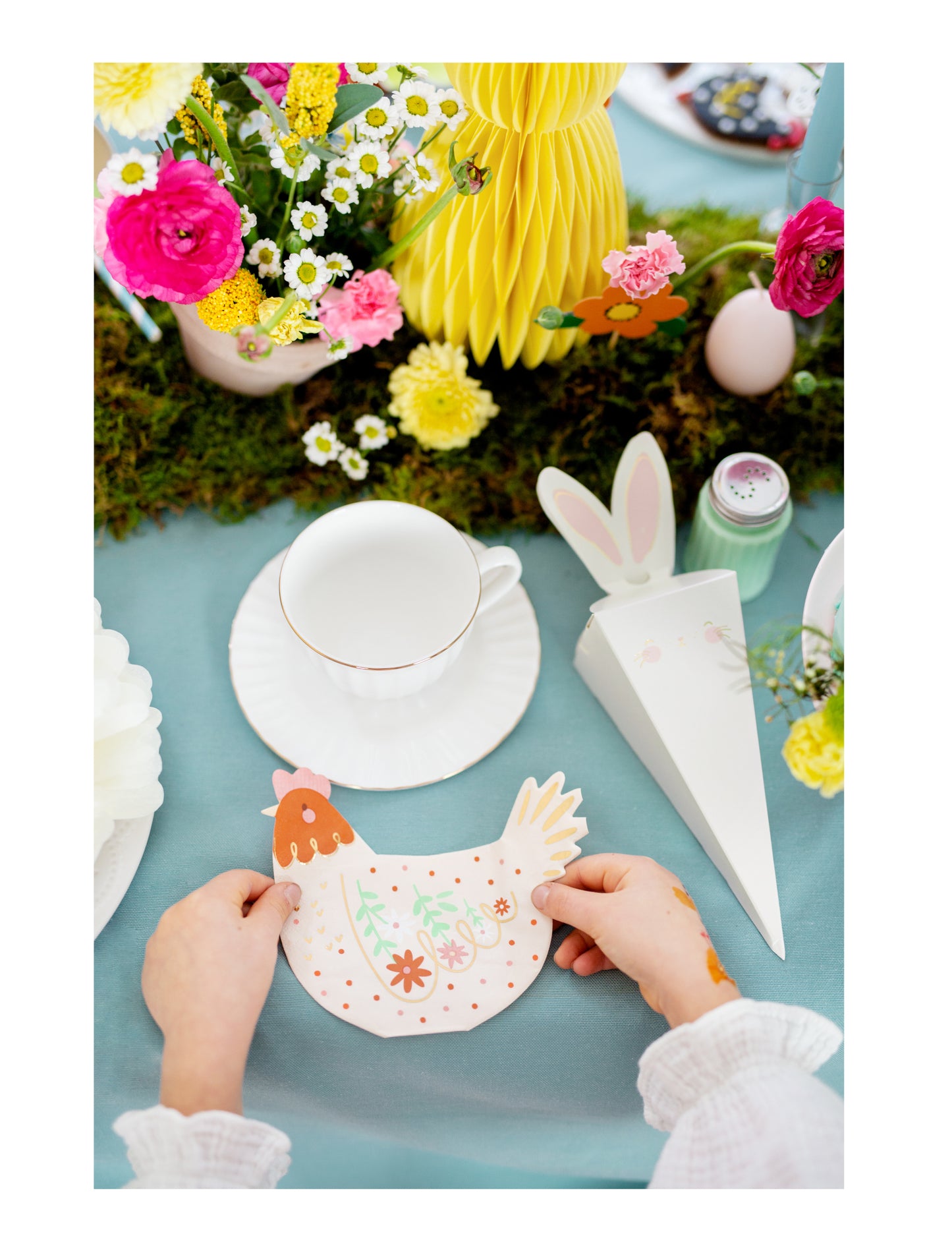 Mise en situation sur une table de fête de la serviette en papier poule de Pâques motifs fleurs