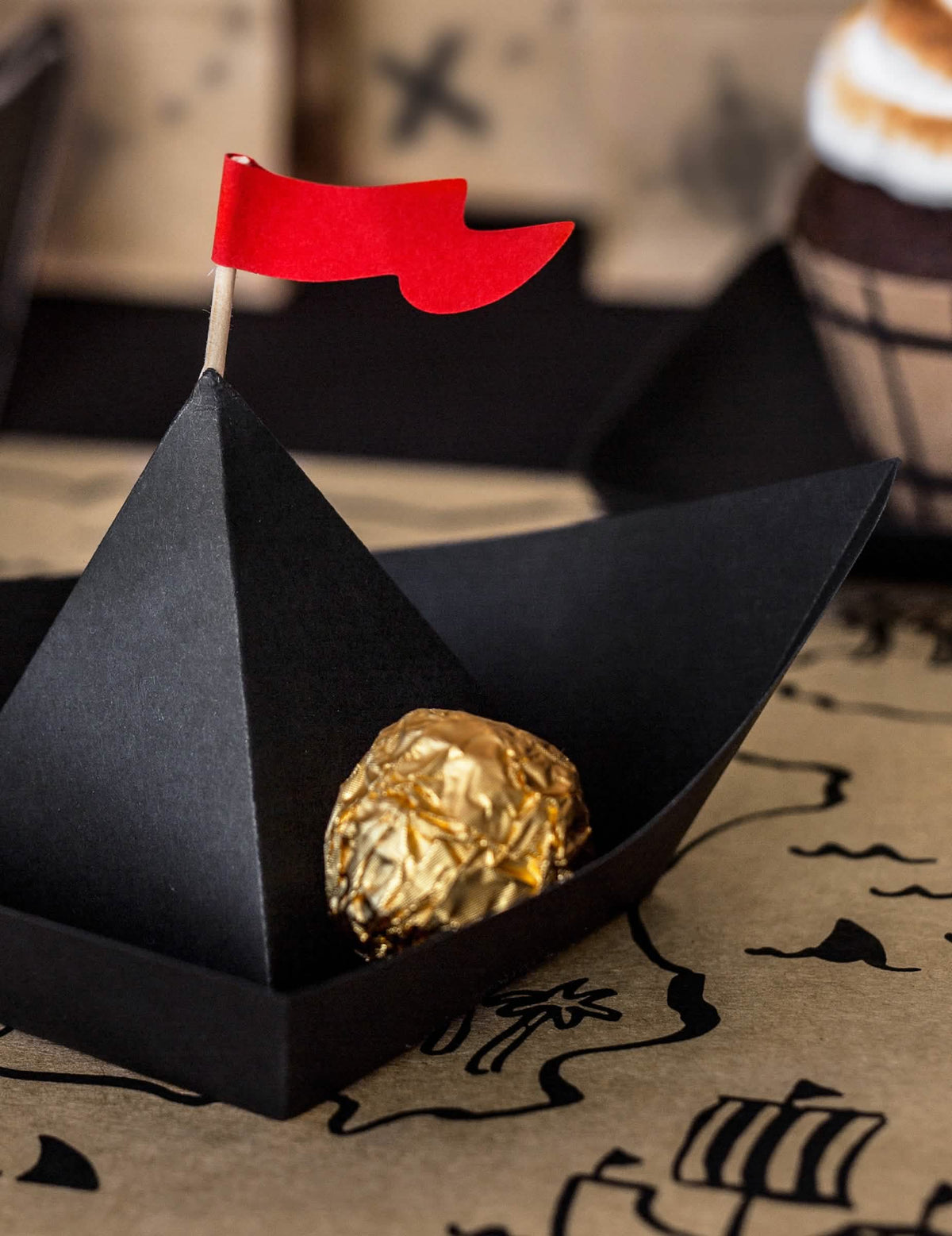 Ciocolată auriu plasată în interiorul bărcii de pirat din hârtie origami pirate