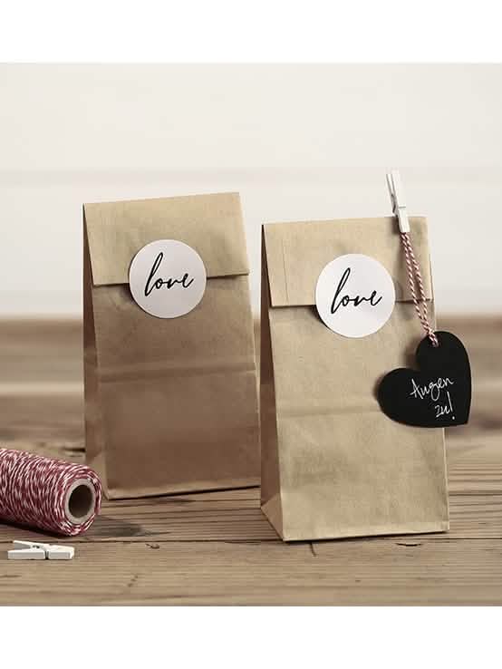 Aranjare decorativă a pliculețelor kraft cu stickere love pentru nuntă