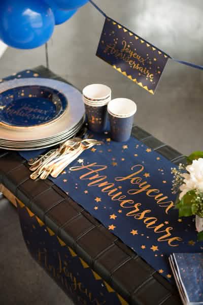 Mise en situation sur une table du chemin de table coton Joyeux anniversaire bleu marine et or