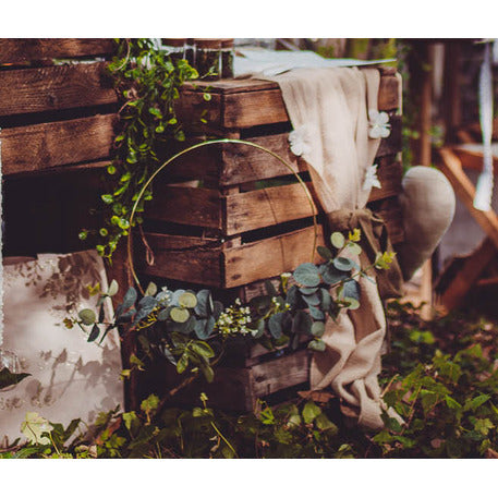 Mise en situation sur des caisses en bois de la couronne en métal d'eucalyptus et fleurs blanches cercle or