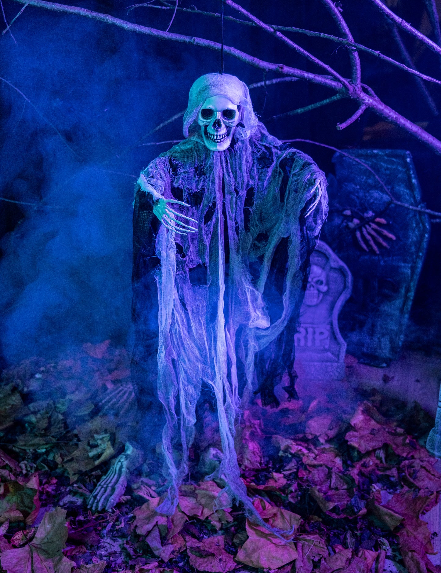 Mise en situation dans un décor de cimetière de la décoration faucheur squelette à suspendre