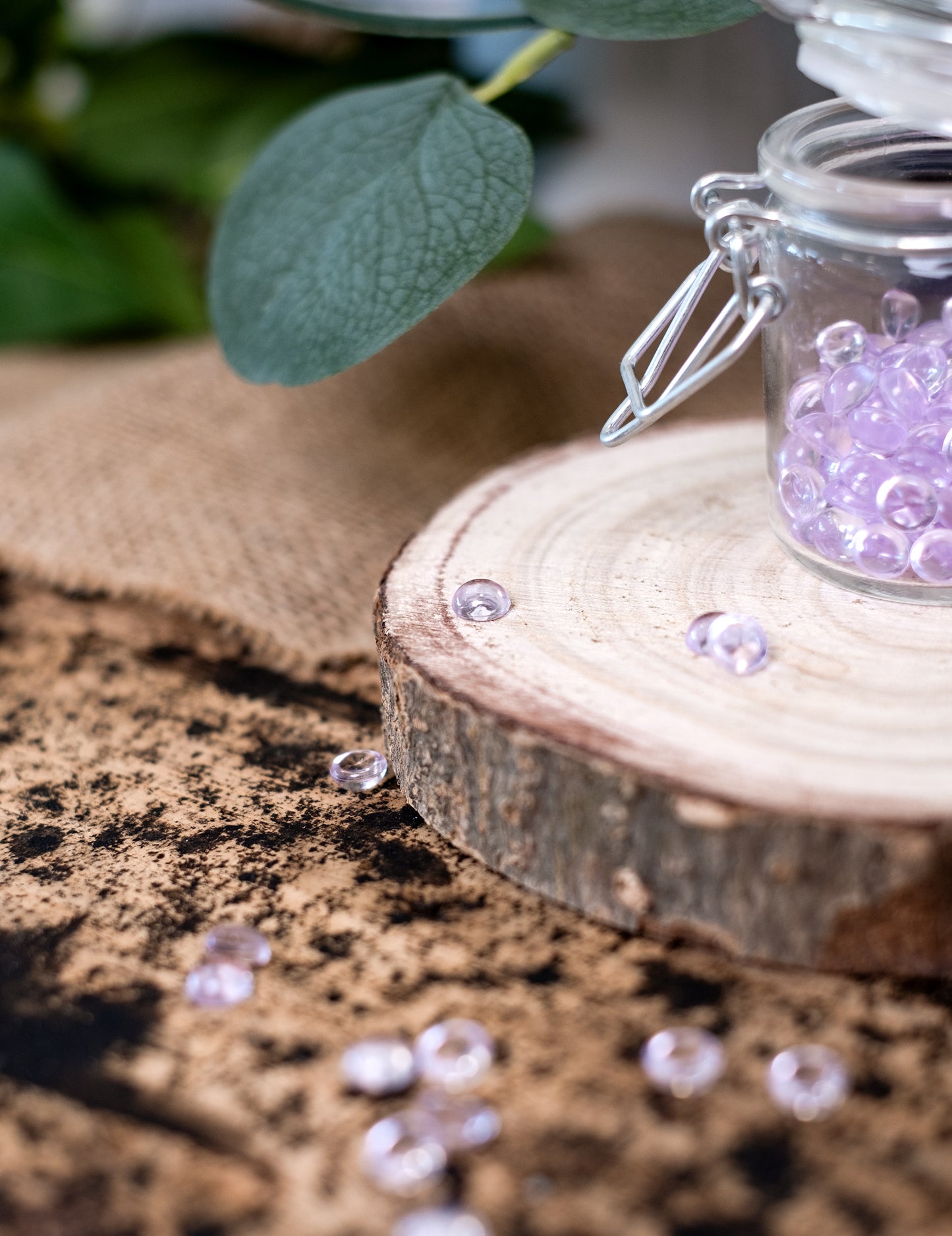 Détail des perles éparpillées sur le rondin de bois des perles effet goutte de pluie pour décoration de table parme