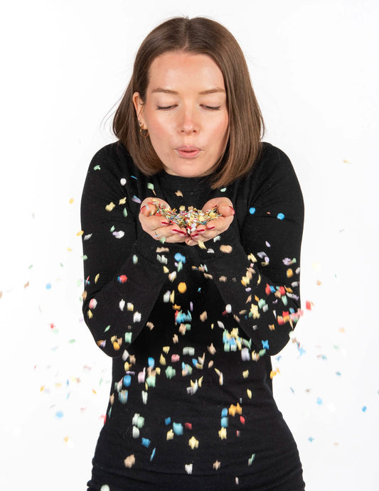 Femme soufflant les confettis du sachet de confettis de carnaval pour fête