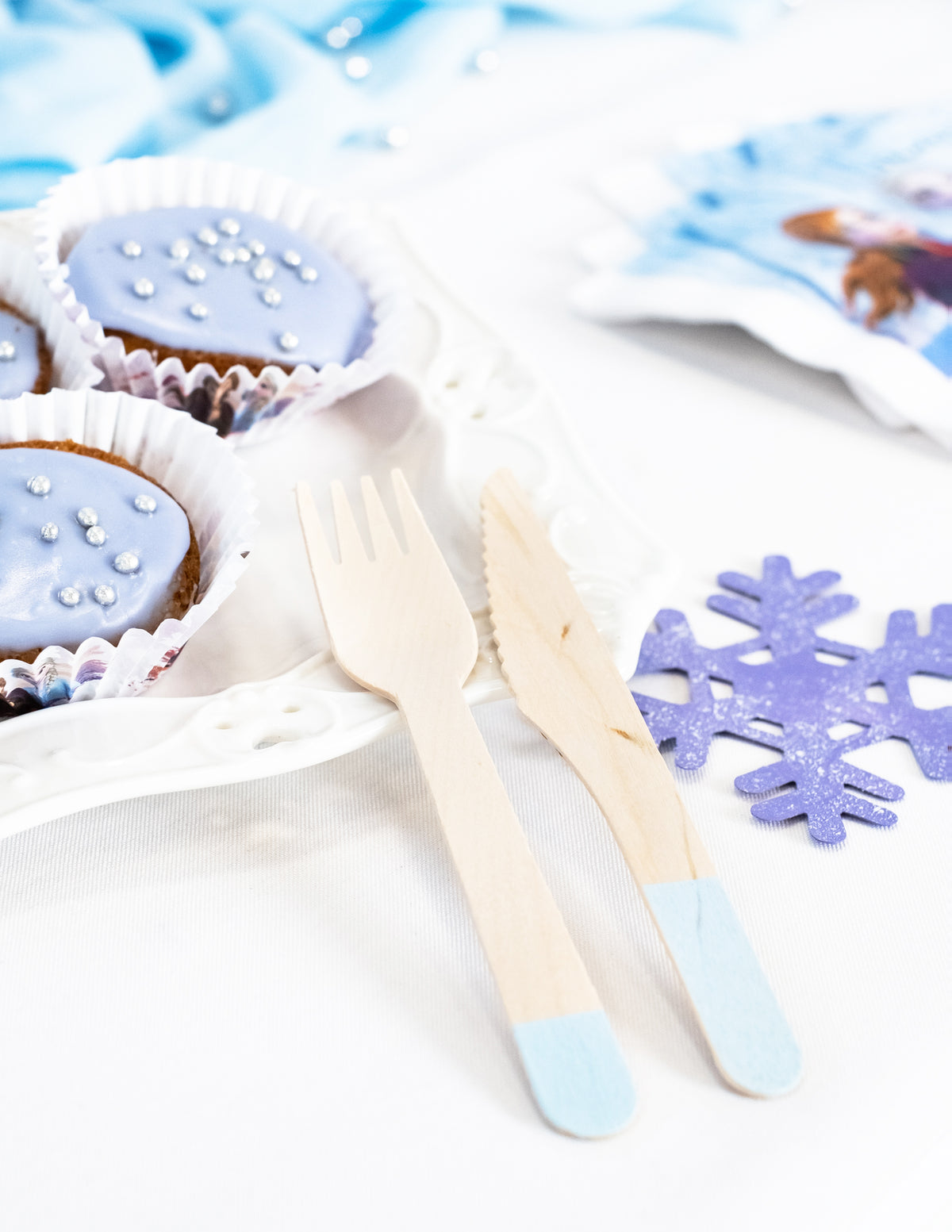 Mise en scène avec cupcakes et flocon de neige des couverts en bois pour fête bleu ciel