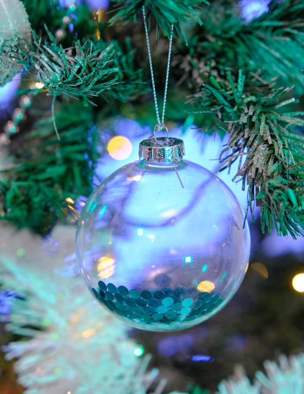 Vue rapprochée des boules en verre de Noël pour sapin transparentes avec paillettes bleues