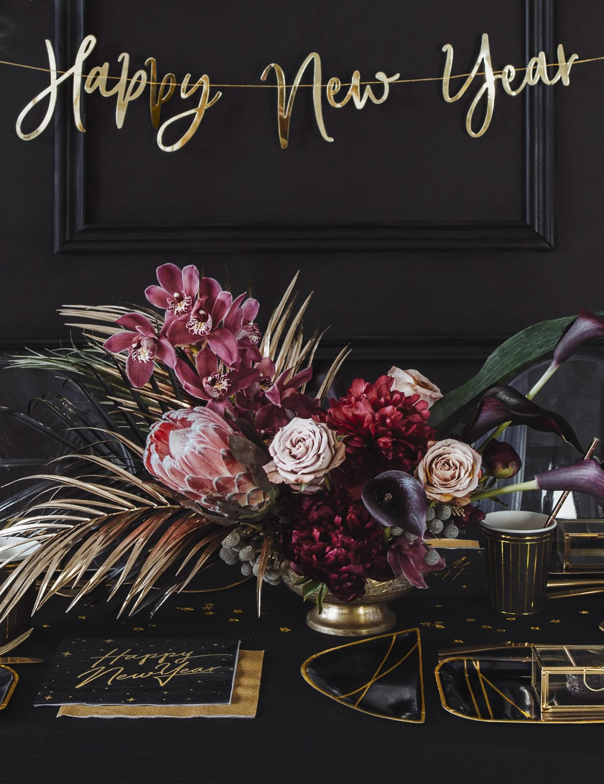 Aranjate pe o masă de petrecere cu șervețele de hârtie Happy New Year negre și aurii, cu decor înstelat