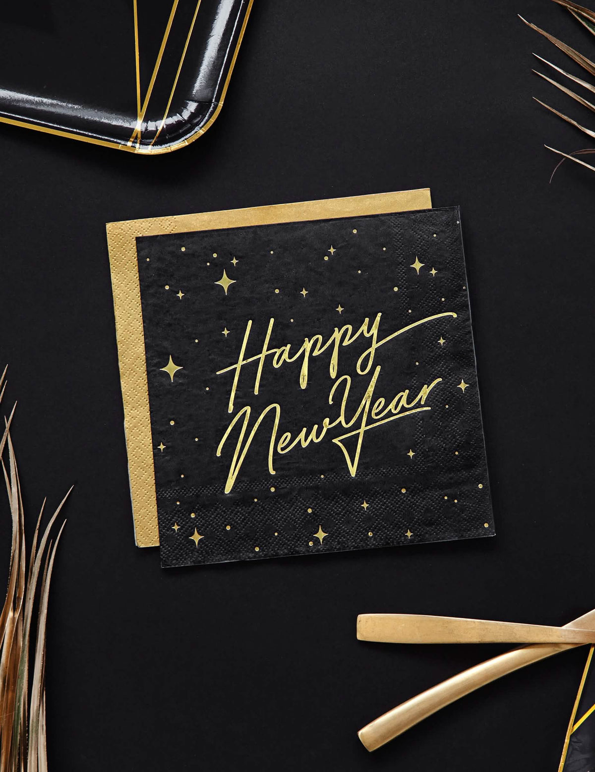 Vedere de sus a șervețelelor de hârtie Happy New Year negre și aurii cu decor înstelat
