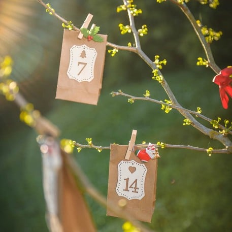 Mise en scène en calendrier de l'Avent des petits sachets kraft pour invités marron avec étiquettes et ficelles blanches