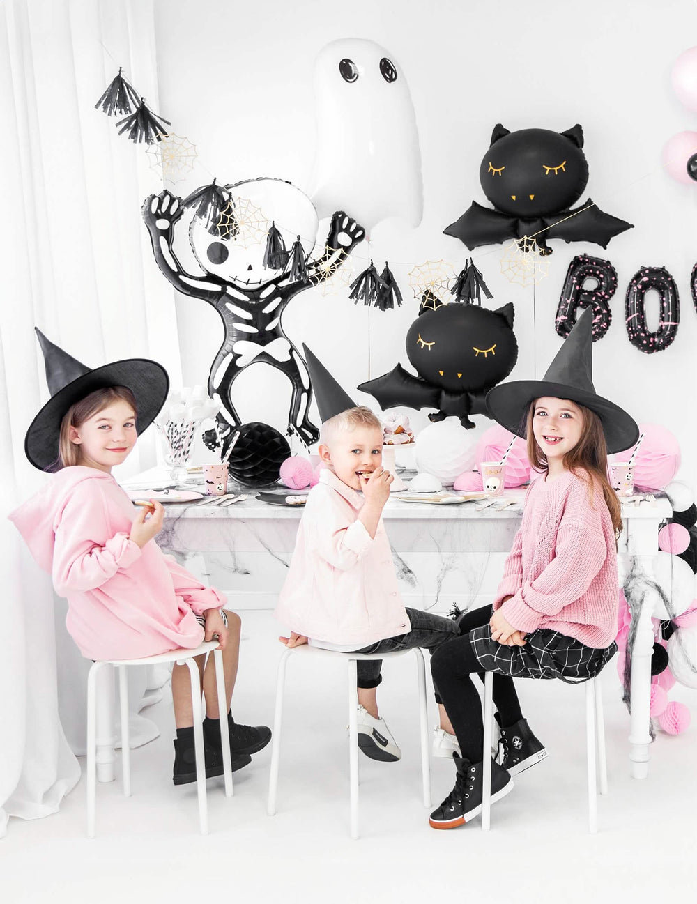 Gustare de halloween cu copii la masă, cu balon din aluminiu în formă de liliac