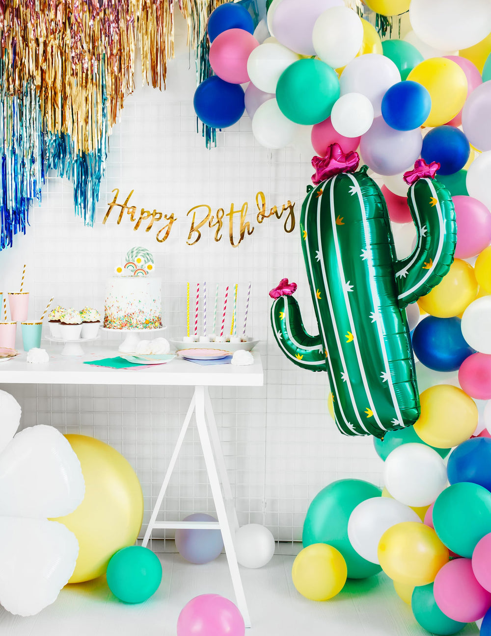 Mise en scène de fête d'anniversaire avec buffet et arche de ballons du ballon cactus en fleurs