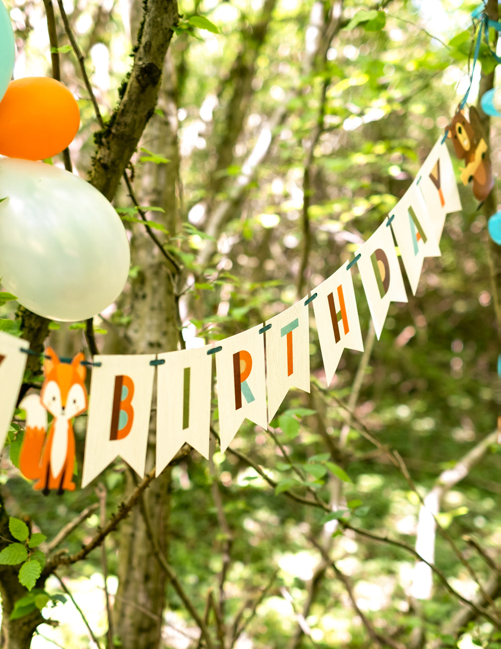 Mise en situation en extérieur de la bannière en carton happy birthday animaux de la forêt