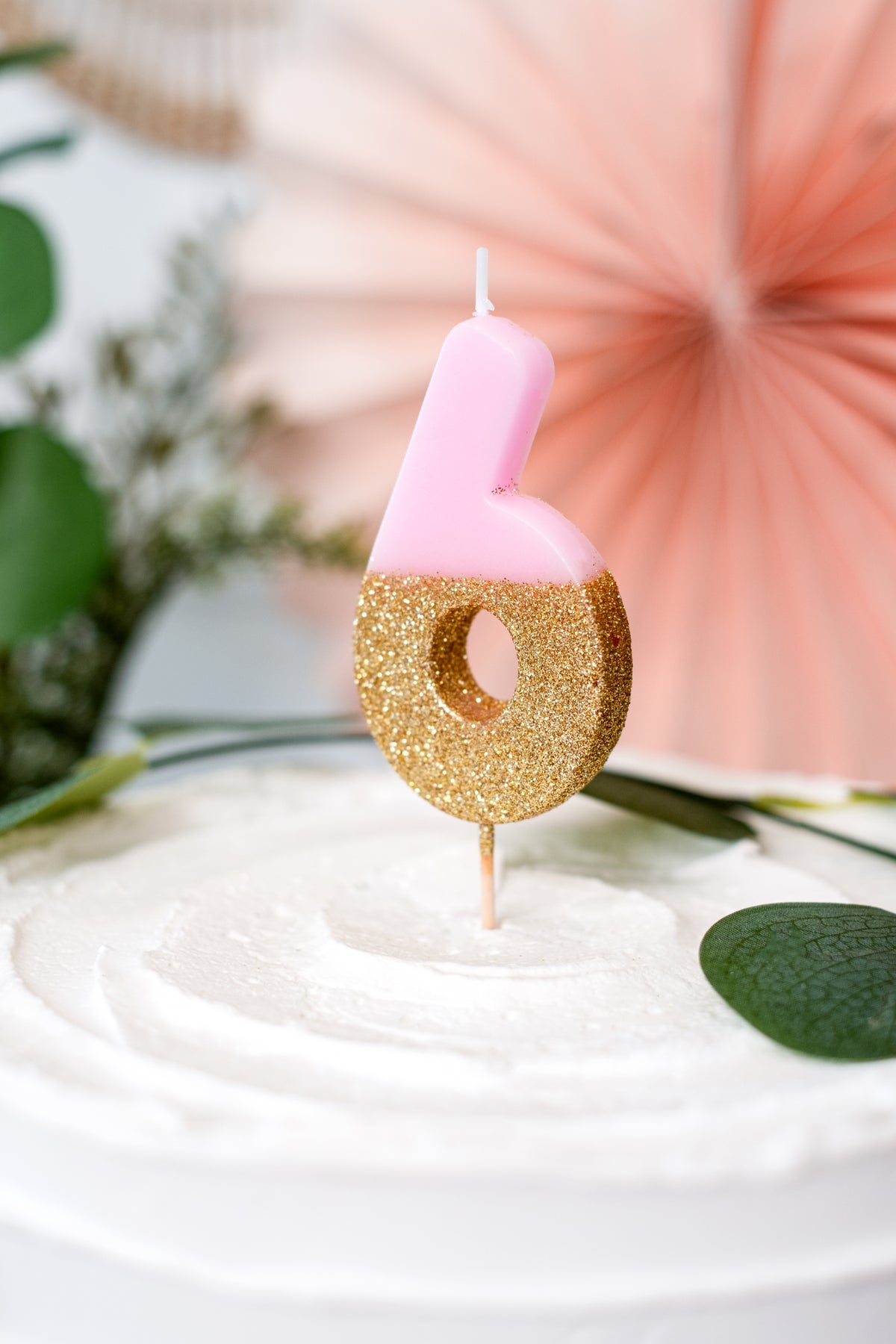 Gros plan de la bougie sur pique chiffre 6 pour gâteau rose et dorée pailletée
