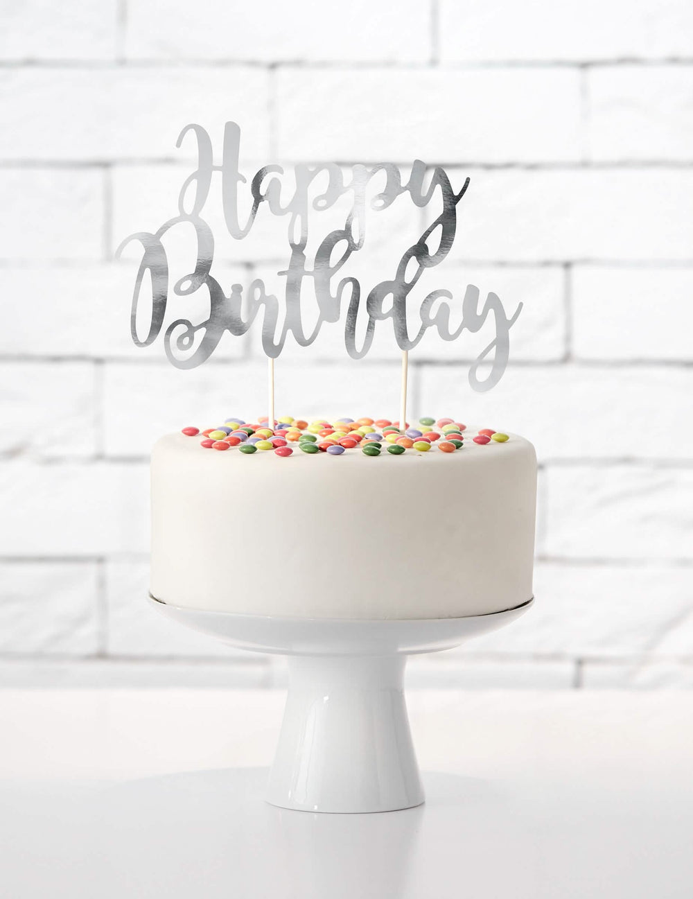 Vedere de ansamblu asupra unui tort cu cake topper happy birthday argintiu metalizat