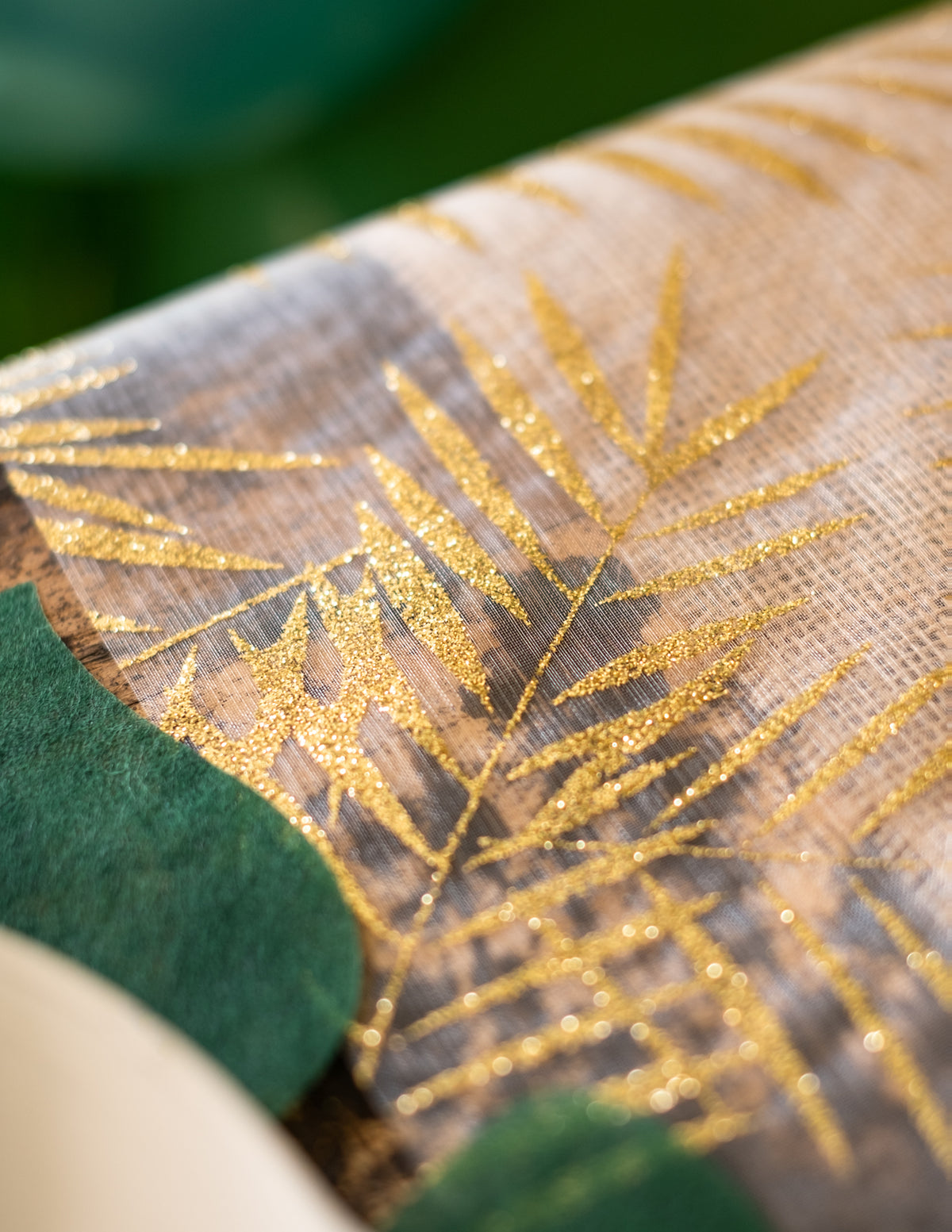 Gros plan sur la texture du chemin de table en organza palmier pour décoration tropicale chic pailleté doré