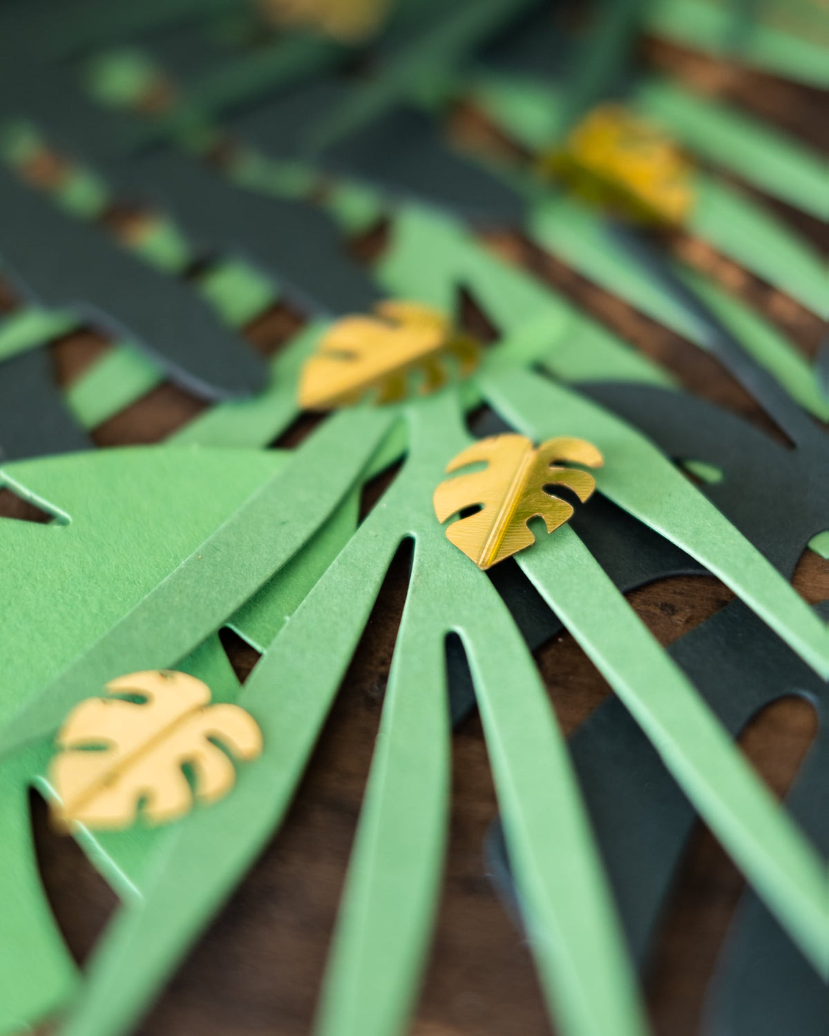 Détail des feuilles dorées sur les feuilles vertes du confettis de table feuilles tropicales