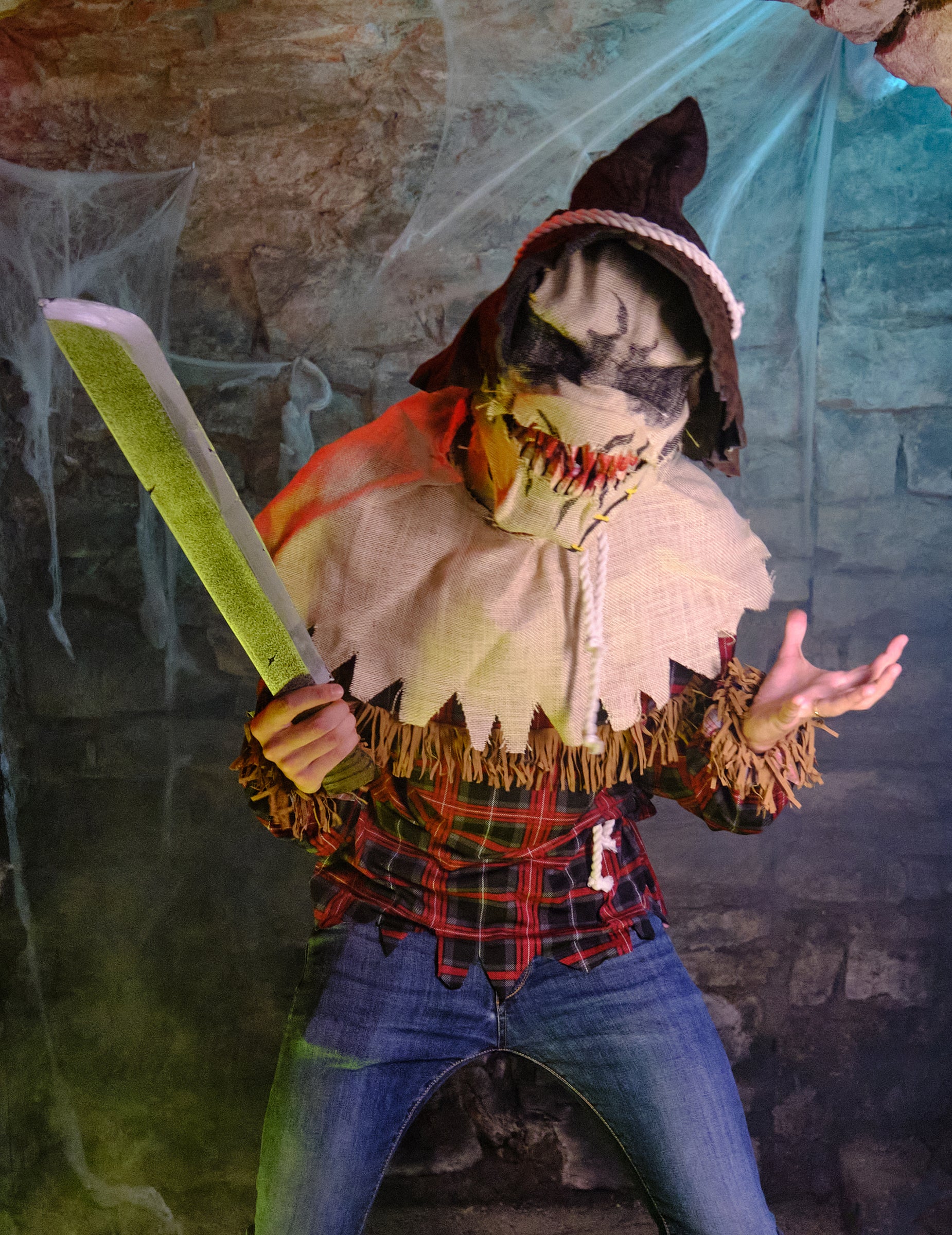 Machete factice tenue par le personnage du déguisement épouvantail avec masque luxe
