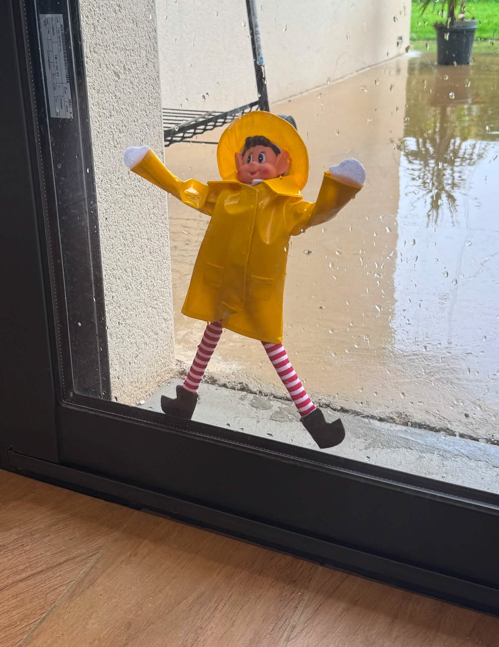 Mise en scène sur une vitre pluvieuse du déguisement imperméable de lutin farceur pour poupée