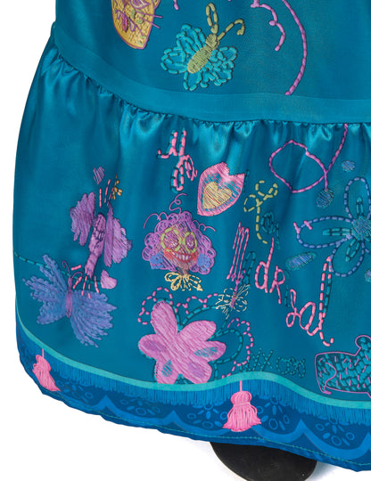 Gros plan sur les pompons et broderies du bas de la jupe du déguisement Mirabel deluxe Encanto™
