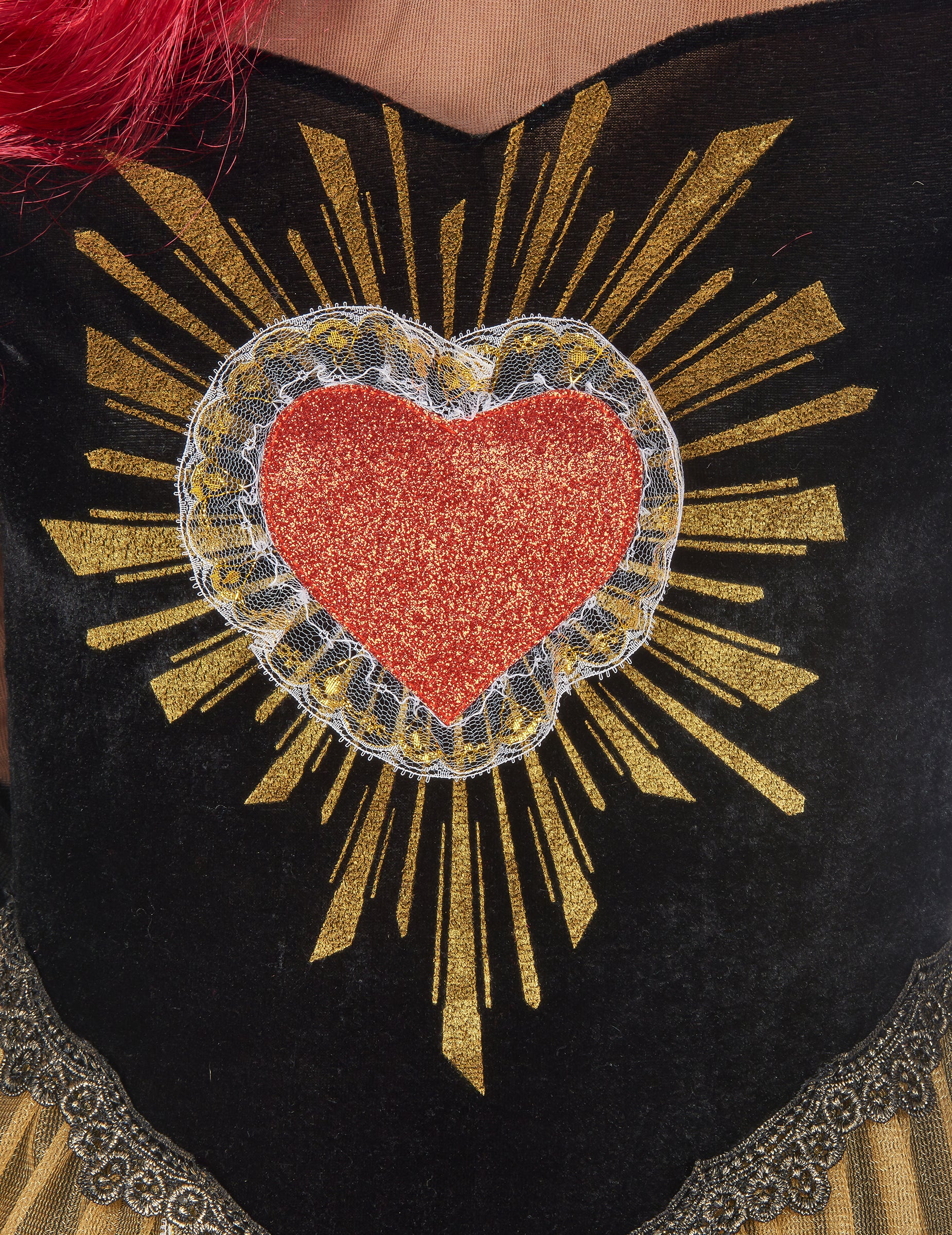 Gros plan sur le motif coeur pailleté avec rayons dorés du déguisement reine du Dia de los muertos
