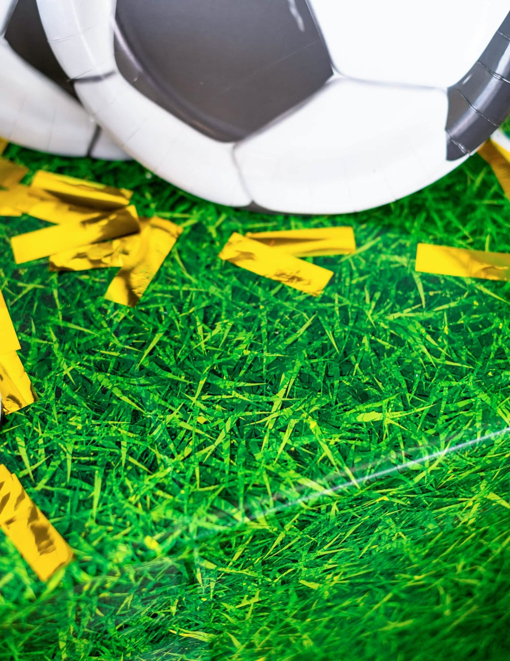 Detaliul confetti aurii și al farfuriei balon a feței de masă din plastic cu efect de iarbă verde