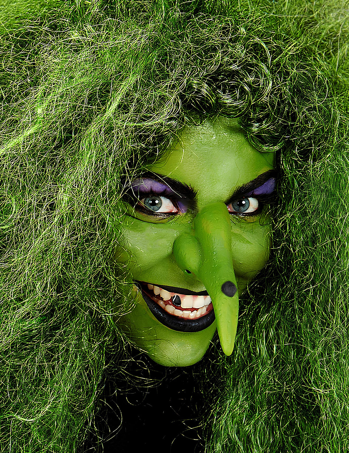 Gros plan sur le visage maquillé en sorcière du maquillage professionnel à l'eau pour visage et corps vert