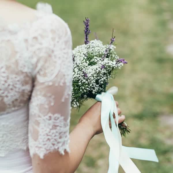 Detaliu al panglicii legate pe un buchet de flori din panglică satinată pentru nuntă